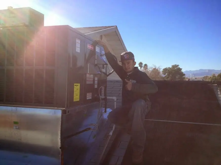HVAC technician performing Air Duct Repair on a rooftop unit in Warwick